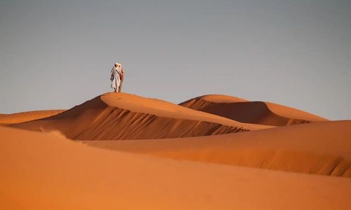 Désert avec un nomade en haut de la dune